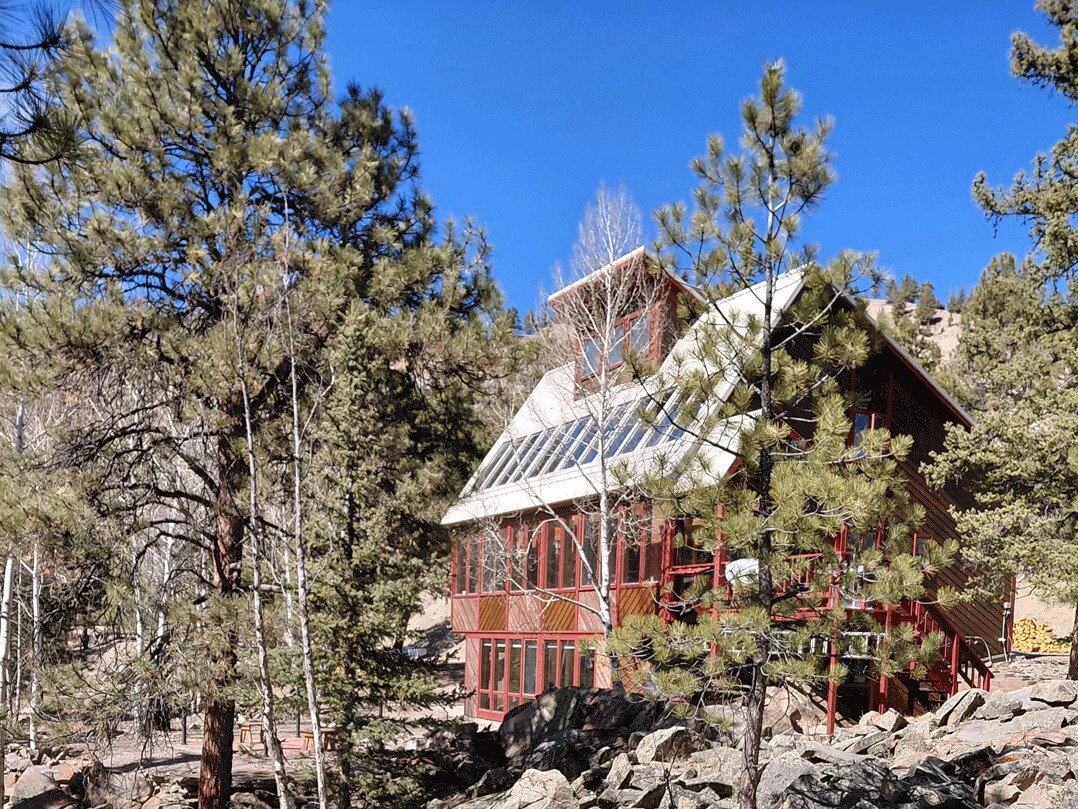 Mountain cabin rental near Lake City surrounded by pine trees, featuring a two-story wood home with large windows and peaceful forest setting in Riverside Estate